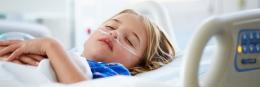 Young girl lies sleeping in hospital bed