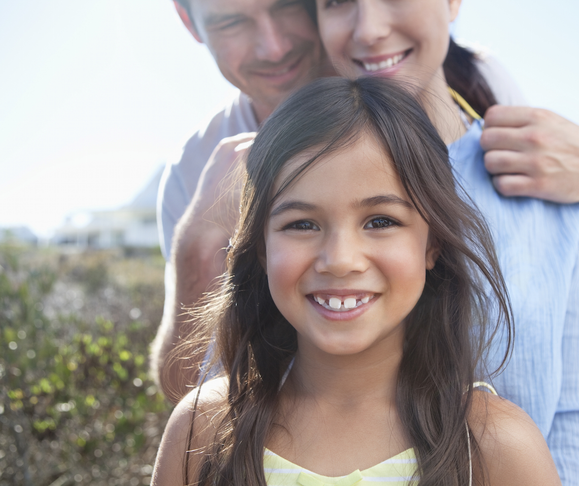 Young smiling girl with her parents outside