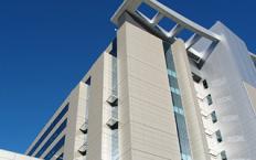 A modern multi-story building with a distinctive architectural design against a clear blue sky.