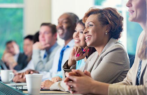 Women and men smile around a board room table