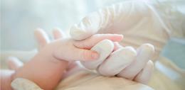 Close-up of infant's hand with hospital gloves